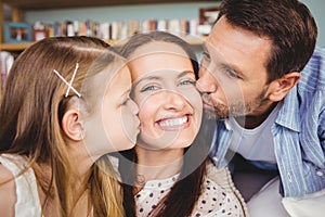 Close-up of father and daughter kissing mother