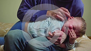 Close up father drips medicine into the ear of a sick boy.