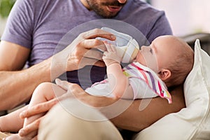 Close up of father feeding baby from bottle