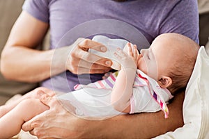 Close up of father feeding baby from bottle