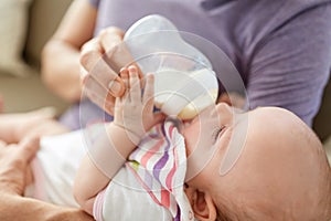 Close up of father feeding baby from bottle