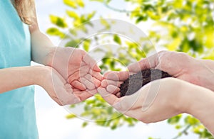 Close up of father and girl hands holding sprout