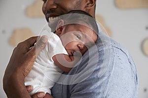 Close Up Of Father Holding Newborn Baby Son In Nursery