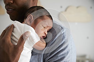 Close Up Of Father Holding Newborn Baby Son In Nursery