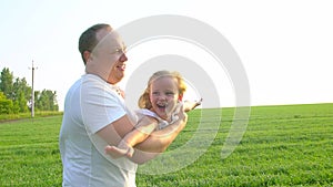 Close-up of father and little cute happy girl playing together. Young father rotates his daughter in hands. Child