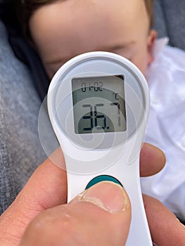 Close-up of a father`s hand taking a baby`s temperature with a thermometer