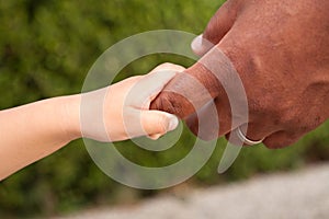 Close up of a father and son holding hands.