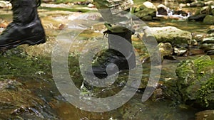 close-up . feet in ankle boots step into a mountain stream, passing it into a ford