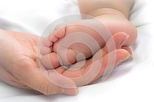 Close-up feet of baby in the hand of mother.