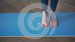 A close-up of the feet of a barefoot woman standing on a rug and getting on her toes. The concept stretching.