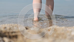 Close-up of feet on the beach, going into the water