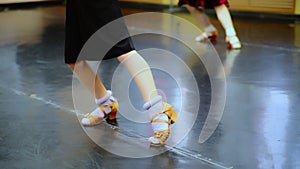 Close-up feet of Caucasian girl in beige high-heels making ballet step in slow motion. Unrecognizable children