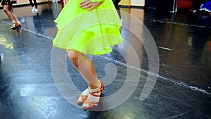 Close-up feet of Caucasian girl in beige high-heels making ballet step in slow motion. Unrecognizable children