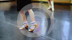 Close-up feet of Caucasian girl in beige high-heels making ballet step in slow motion. Unrecognizable children