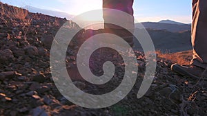 Close up of feet climber male hiker traveler man walking and climbing up in rocky top mountain at sunset