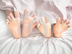 Close-up of the feet of a couple on the bed