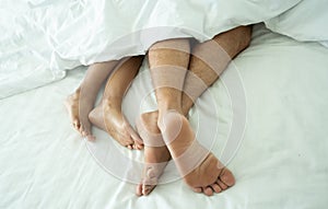 Close up of the feet of a couple on white bed