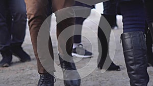 Close-up of feet of crowd of people in city. Crowds of human feet trample on dirty snow in city in winter. Urban