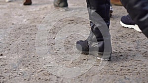 Close-up of feet of crowd of people in city. Crowds of human feet trample on dirty snow in city in winter. Urban