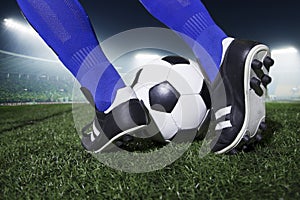 Close up of feet kicking the soccer ball, night time in the stadium