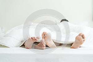 Close up feet of male gay couple lying down on bed, cover with blanket. Romantic man LQBTQ starting foreplay and making love,