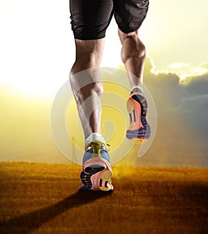 Close up feet with running shoes and strong athletic legs of sport man jogging in fitness training sunset workout