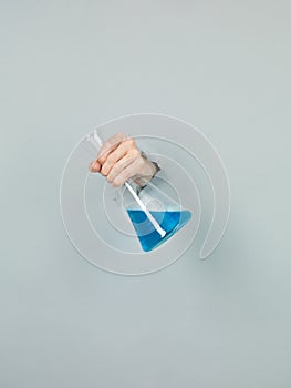 close-up of femal hand holding a chemistry flask with blue liquid