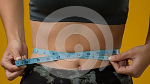 Close up female abdominal body part tummy cropped view unrecognizable sport woman with measuring tape measure waist