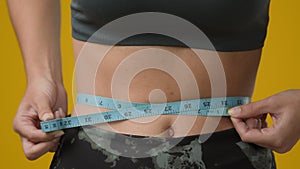 Close up female abdominal body part tummy cropped view unrecognizable sport woman with measuring tape measure waist