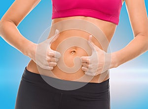 Close up of female abs and hands showing thumbs up