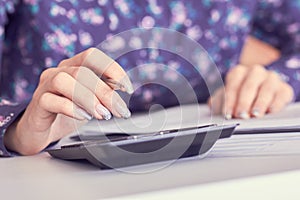 Close up of female accountant or banker hand making calculations. Savings, finances and economy concept