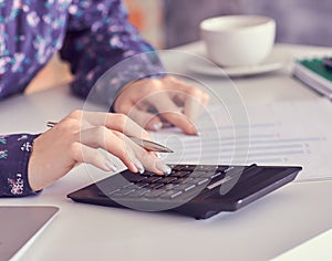 Close up of female accountant or banker hand making calculations. Savings, finances and economy concept