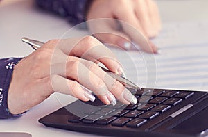 Close up of female accountant or banker hand making calculations. Savings, finances and economy concept