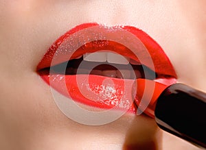 Close up of female applying bright red lipstick makeup. Professional fashion make-up. Bright red lipstick