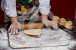 Close up of female baker hands kneading dough and making bread with a rolling pin