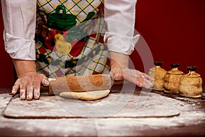 Close up of female baker hands kneading dough and making bread with a rolling pin