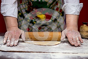 Close up of female baker hands kneading dough and making bread with a rolling pin