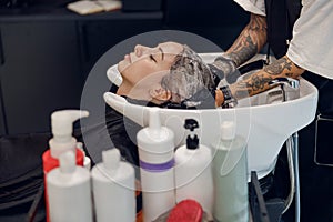 Close up of female barber washes the hair of woman in beauty salon