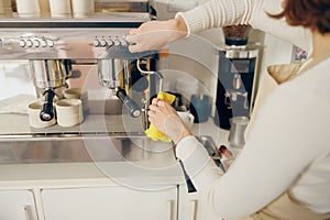 Close up of female barista cleaning coffee machine at coffee shop after froths milk photo
