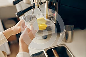 Close up of female barista froths milk on a coffee machine for making cappuccino or latte photo