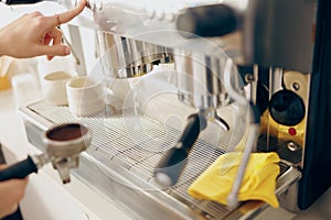 Close up of female barista making coffee in a coffee machine working in cafe. High quality photo
