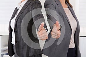 Close-up of female business team holding their thumbs up