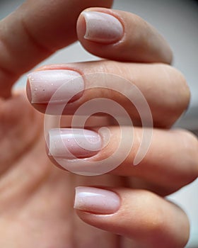 Close-up of a female with carefully manicured pastel pink fingernails