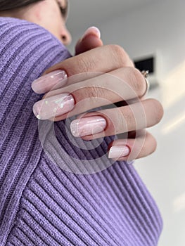Close-up of a female with carefully manicured pastel pink fingernails