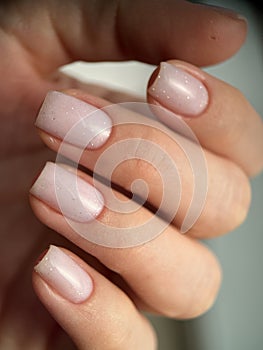 Close-up of a female with carefully manicured pastel pink fingernails