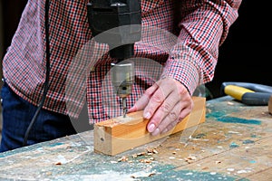 Close-up of female carpenter drilling wooden plank to make hole. DIY, woodwork concept