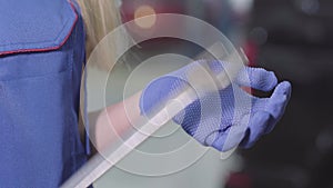 Close-up of female Caucasian hands in work gloves holding adjustable wrench. Unrecognisable blond female auto mechanic