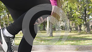 Close-up of female Caucasian legs in sports trousers stopping during the run because of pain in the knee. Female runner