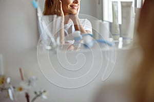 Close up of female chin and smile in mirror in bathroom. Perfect skincare concept.