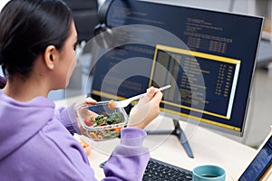 Close up of female computer programmer eating takeout lunch at workplace photo